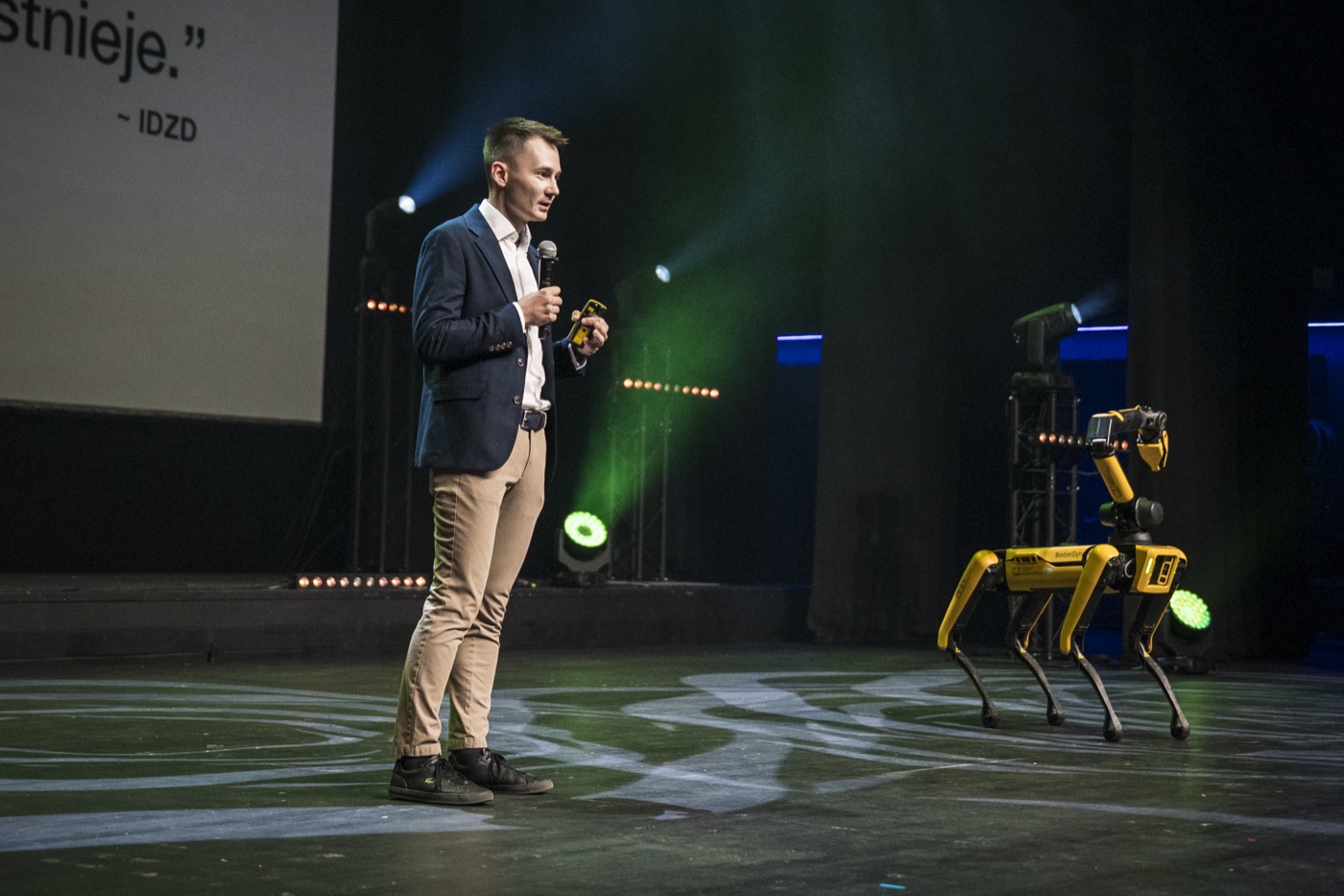 Rafał Garbacz prowadzi wystąpienie o AI dla firm na scenie z robotem Spot